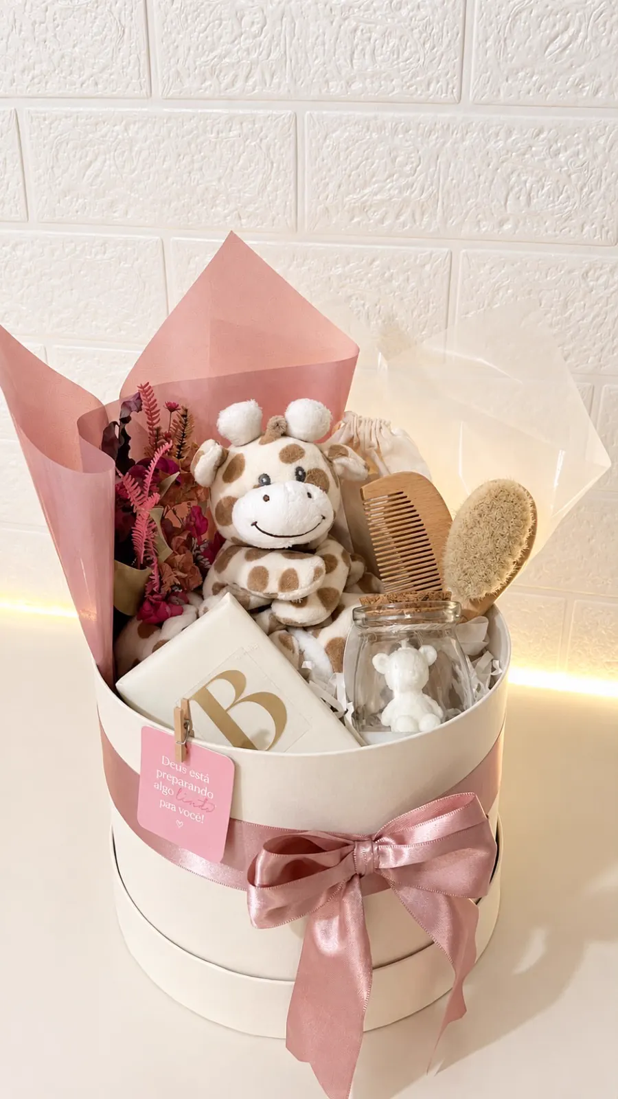 Cesta de presente de bebê: caixa redonda com laço rosa, girafa de pelúcia, escova e flores secas